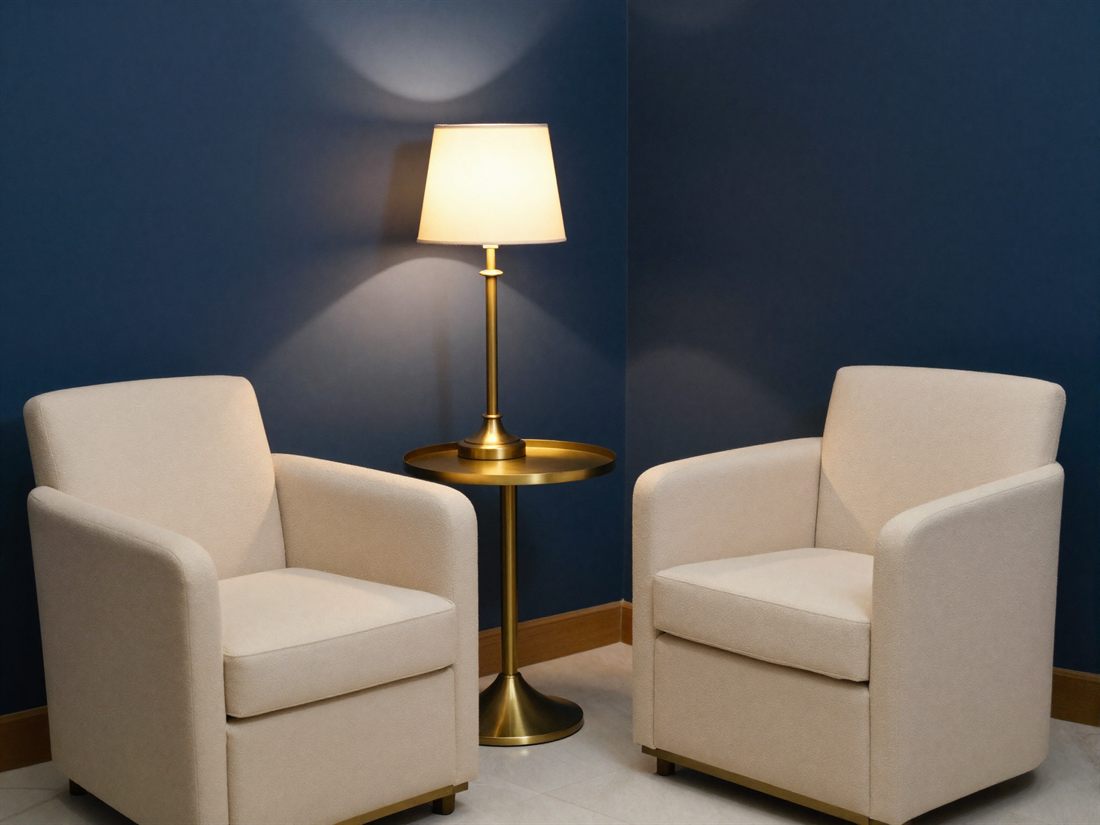 The consultation corner at The Nightingale Wellness Clinic: two cream armchairs in warm lamplight against navy walls