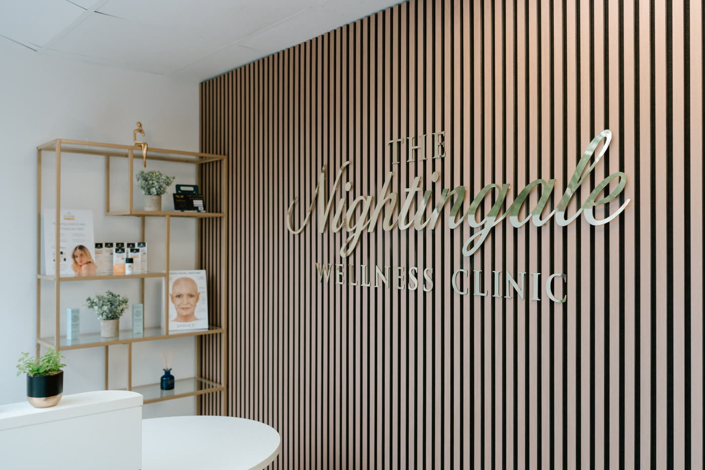 The welcoming reception area at The Nightingale Wellness Clinic: navy walls, warm gold lighting and cream armchairs